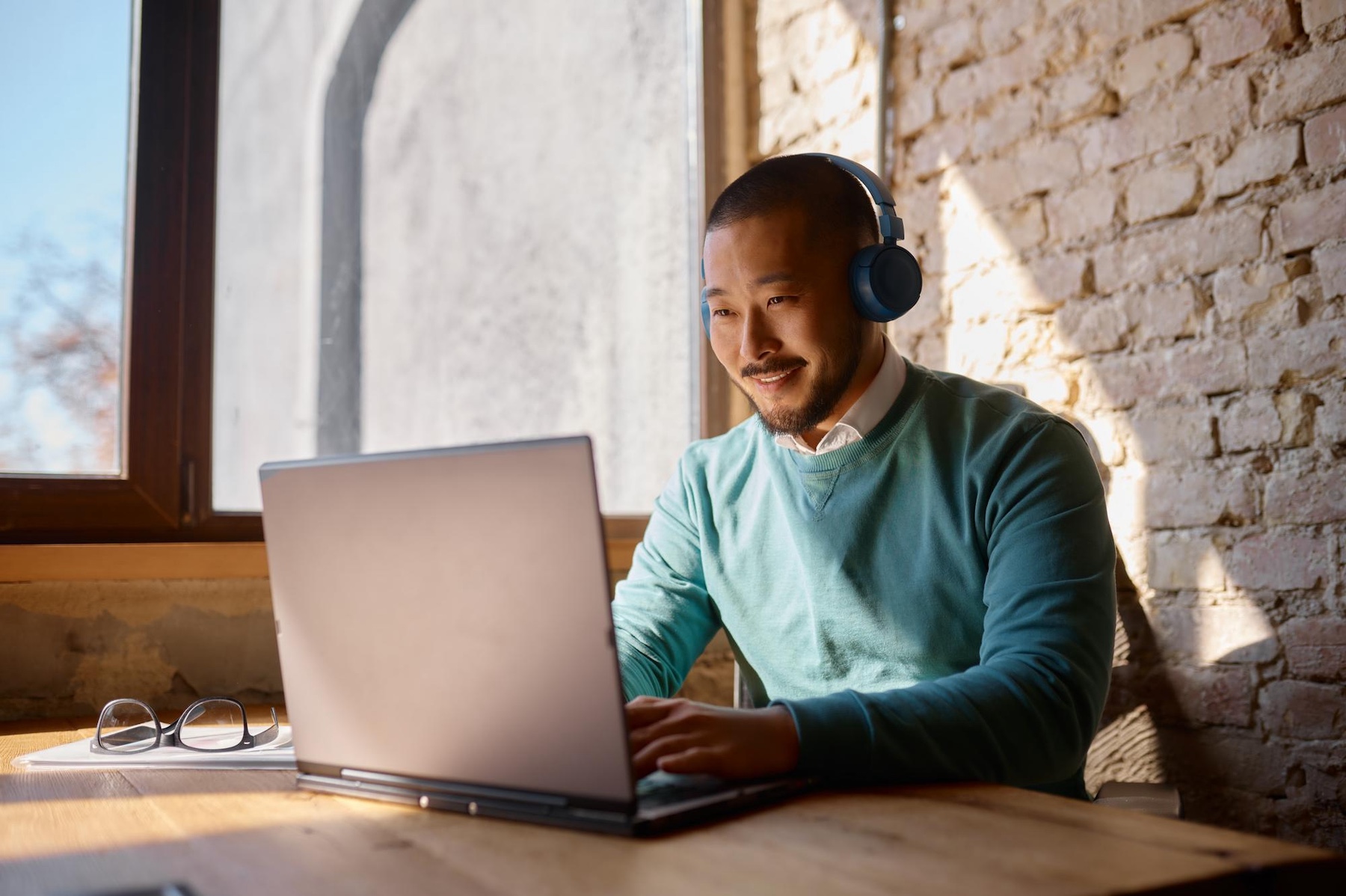 man with headphones speaking into his computer