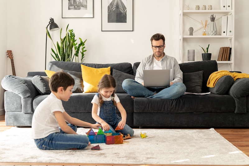 Busy parent with laptop watching kids play